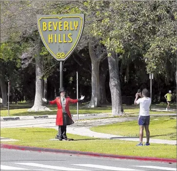  ?? Photograph­s by Mel Melcon Los Angeles Times ?? GREGG DONOVAN, left, the former "Ambassador of Beverly Hills," has a passerby take his photograph. The state has warned the city that it will face heavy fines if it does not cut water consumptio­n by 36%.