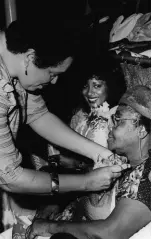  ?? FILE PHOTOS ?? Barbara Gloudon, chairman of the Little Theatre Movement, pins a corsage on Gloria Dehring at the 100th performanc­e of the LTM Pantomime ‘Tantaloo’ in 1983. Looking on is Mrs Alistair McBeath, wife of the CEO of the Carreras Group of Companies, which treated its employees.