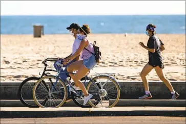  ?? Gina Ferazzi Los Angeles Times ?? TWO BICYCLISTS and a runner wear masks in Santa Monica in early July. Glitches cast doubt on virus data.