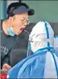  ?? AP ?? A worker swabs a man’s throat for a Covid-19 test in Beijing, China, on Thursday.