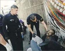  ?? Patrick T. Fallon For The Times ?? LAPD officers tend to a man who has fallen ill on skid row. Health officials say it’s impossible to know what’s in each batch of spice.