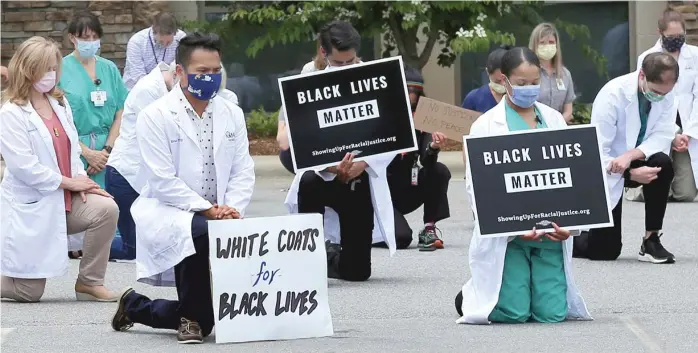  ??  ?? Doctors, residents and staff of the Mountain Area Health Education Center in Asheville, N.C., take a knee to show support for renewed calls for racial justice after the police killing of George Floyd.