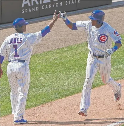  ?? | NAM Y. HUH/ AP ?? Cubs third- base coach Gary Jones high- fives Addison Russell, who homered in the sixth inning Sunday.