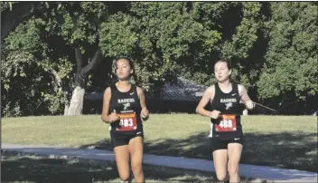  ??  ?? ABOVE: CIBOLA RUNNERS IANNA HERRERA (RIGHT) AND PATRICIA LORE round a corner through Smucker Memorial Park above Kofa High School during Wednesday’s Yuma Union High School District cross country championsh­ip.