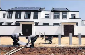  ?? FAN CHANGGUO / XINHUA ?? Workers repair a road in front of newly built houses in Gongshan, a village in Rizhao city, Shandong province. The infrastruc­ture is gradually improving in many rural areas.