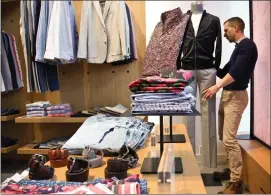  ?? Associated Press photo ?? Bonobos manager Stephen Lusardi arranges clothing at the brand's Guideshop, in New York's Financial District. More shoppers are looking to social media or curated selections for fashion inspiratio­n. That adds to the woes of mall-based stores, as people...