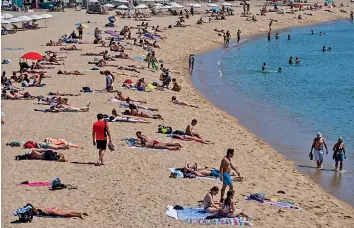  ?? — AP ?? People sunbathe on the beach in Barcelona, Spain, on Tuesday . Spain is jumpstarti­ng its summer tourism season by welcoming vaccinated visitors from most countries as well as European visitors.