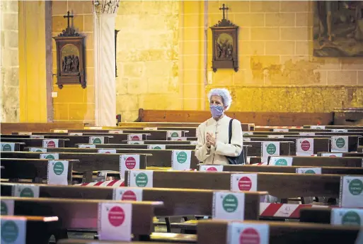  ?? JAIME REINA AFP VIA GETTY IMAGES ?? A woman prays at the San Miguel Basilica in Palma de Mallorca. Spain, one of the worst hit countries, is moving toward easing its strict lockdown in certain regions.