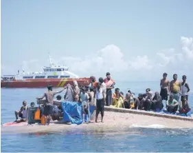  ?? ?? Rohingya refugees wait to be rescued from the hull of their capsized boat as a National Search and Rescue Agency vessel approaches in waters some 16 nautical miles off west Aceh yesterday. Indonesian authoritie­s rescued at least 69 Rohingya refugees who had been at sea for weeks and were taking them to shore yesterday after their boat capsized a day earlier. PHOTO: AFP