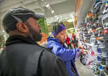  ??  ?? Mike Oliver of Swissvale looks on as his daughter, Shelby King-Oliver, of Rankin reacts to the price of a pair sneakers at Monroevill­e Mall in Monroevill­e.