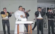  ??  ?? El padre Francisco Mukul Domínguez ante el pastel por sus 25 años de sacerdocio mientras el mariachi Alma Mexicana le canta. A la izquierda, el equipo de caridad de la parroquia de Progreso le entrega un regalo