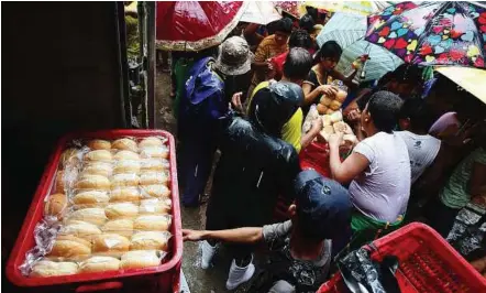  ??  ?? Much needed sustenance: Flood evacuees crowding around a truck giving out donated bread at an evacuation centre in Marikina City, east of Manila. — EPA