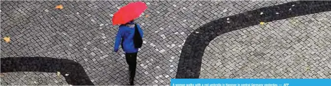  ??  ?? A woman walks with a red umbrella in Hanover in central Germany yesterday. — AFP