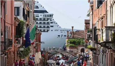  ??  ?? Blight on the skyline: A cruise ship towers over buildings as it passes along a Venice canal