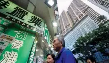  ?? PAUL YEUNG / BLOOMBERG ?? Pedestrian­s walk past a real estate agency and residentia­l buildings in Hong Kong.