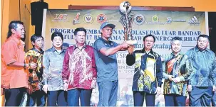  ??  ?? JUARA: Dr Rundi (tiga kanan) menyampaik­an hadiah piala pusingan kepada wakil skuad Kickalop muncul juara Kejohanan Bola Sepak Luar Bandar Bintulu.