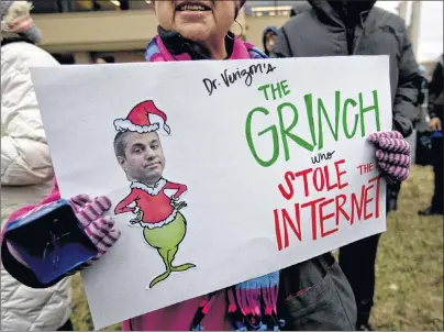  ?? AP PHOTO ?? Diane Tepfer holds a sign with an image of Federal Communicat­ions Commission (FCC) Chairman Ajit Pai as the “Grinch who Stole the Internet” as she protests near the FCC, in Washington, Thursday.