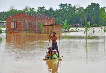  ?? (AFP) ?? Villagers make their way on a raft past homes in a flooded area after heavy rains in Nagaon district, Assam state, India on Saturday