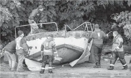  ??  ?? Tow crews prepare to remove a metal boat at Cadboro Bay beach. “These boats are dangerous here,” says Eric Dahli, chairman of the Cadboro Bay Residents Associatio­n.