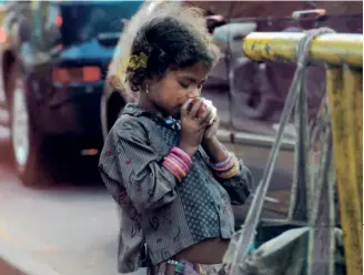  ?? ?? A LITTLE GIRL eating an apple at a traffic signal in New Delhi in February 2015. India was at 55th position in the Global Hunger Index in 2015; it has slipped to 107th.