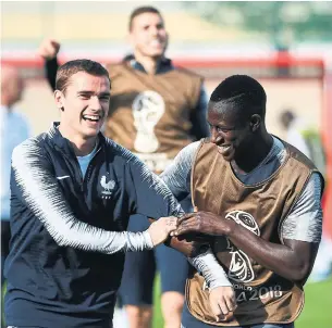  ?? FRANCK FIFE/AFP/GETTY IMAGES ?? Forward Antoine Griezmann, left, who is half-German and half-Portuguese, and left back Benjamin Mendy, who has Senegalese heritage, keep it loose on the eve of the World Cup final.