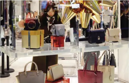  ?? — AP ?? BEIJING: A Chinese woman checks a handbag at an American fashion boutique at an up-scale shopping mall in Beijing yesterday. US Presidente­lect Donald Trump’s announceme­nt that he plans to quit the Trans-Pacific Partnershi­p is drawing vows from other Pacific Rim countries to push ahead with the trade pact while they also pursue free trade deals with China.