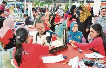  ??  ?? Penduduk menjalani pemeriksaa­n kesihatan yang ditawarkan secara percuma .