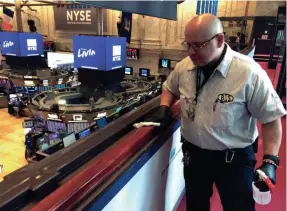  ?? TED SHAFFREY/AP ?? Porter Raul Rodriguez disinfects a railing at the New York Stock Exchange on Monday amid coronaviru­s fears. About 32 million U.S. workers have no paid sick days. Concerns are growing that workers who cannot afford to stay home will accelerate the spread of the virus, Vice President Mike Pence told reporters.