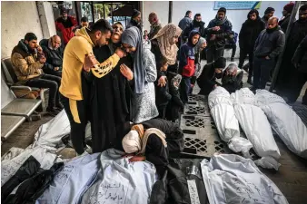  ?? ?? Palestinia­ns grieve over the bodies of loved ones in southern Gaza;