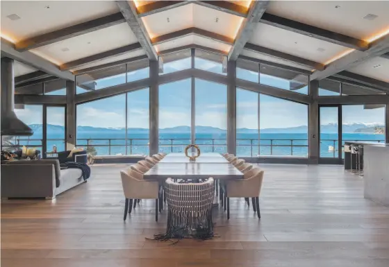  ?? SOLANNA DESIGN ?? Hardwood flooring lines a great room that includes a floating fireplace and floor-to-ceiling windows framing views of Lake Tahoe.