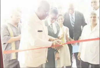  ??  ?? Finance Minister Winston Jordan (second from left) being assisted by a work- study student in the cutting of the ribbon as others, including Minister within the Ministry of Finance Jaipaul Sharma (right), look on.