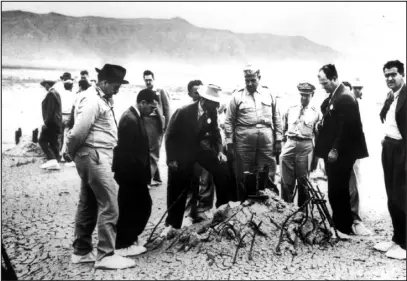  ?? LOS ALAMOS NATIONAL LABORATORI­ES VIA THE NEW YORK TIMES ?? Scientists and military officials — including Maj. Gen. Leslie R. Groves (fourth from left in uniform) and Dr. J. Robert Oppenheime­r, (third from left in brimmed hat and suit) — view the base of the steel tower on which the first atomic bomb was tested at the Trinity Site near Alamagordo, N.M., on July 16, 1945.