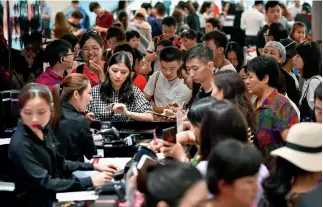  ?? Xinhua ?? 8 de febrero de 2018. Turistas selecciona­n artículos en un centro comercial libre de impuestos en Sanya, provincia de Hainan.