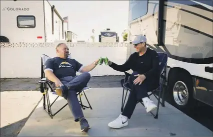  ?? Courtesy of the Chargers ?? NEW CHARGERS offensive coordinato­r Greg Roman, left, and coach Jim Harbaugh offer each other cheers as they enjoy drinks outside Harbaugh’s RV parked at Huntington Beach. “An homage to Rockford? Yeah, that’s a perfect word for it,” Harbaugh said.