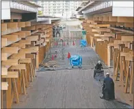  ?? (AP/Hiro Komae) ?? Constructi­on workers fold a tarp sheet at a closed building complex being built as part of the athletes’ village to be used during the postponed Olympic and Paralympic Games in Tokyo.