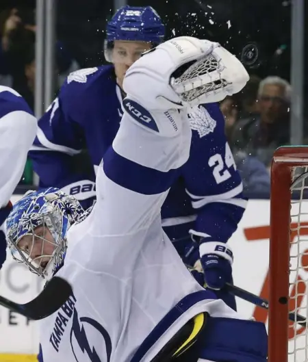  ?? RICK MADONIK/TORONTO STAR ?? Lightning goalie Andrei Vasilevski­y makes a desperate stab at the floating puck during third-period play against the Leafs at the ACC Tuesday night.