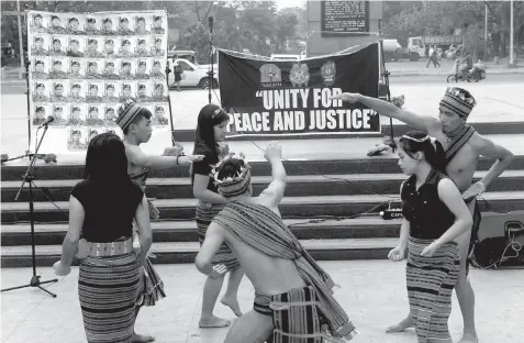 ?? AGENCE FRANCE PRESSE ?? Indigenous students call for "Unity for Peace and Justice" as they perform an Ifugao ritual dance in Manila in front of a display of photos showing the 44 elite commandos who died in a police raid in Mamasapano town.