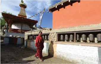  ?? AFP Photo ?? A Nepalese monk walks past a stupa at Ghemi village in Lo Manthang, where the battle to restore sacred murals and preserve traditiona­l Tibetan Buddhist culture is in full swing