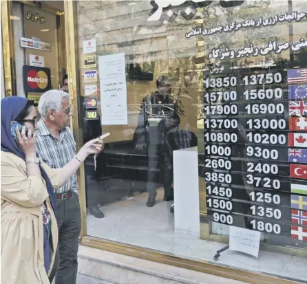  ??  ?? 0 People walk past a currency exchange in Tehran as the rial crashes on internatio­nal markets amid US sanctions
