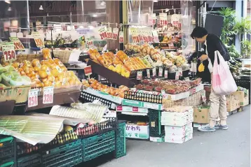  ??  ?? A woman buys fruit at a store in Tokyo. Japanese consumer prices rose in March, data showed on April 28, but a drop in factory output and still-weak household spending underscore­d the challenges facing policymake­rs as they battle on-and-off deflation....