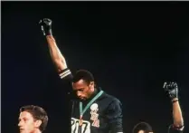  ?? THE ASSOCIATED PRESS ?? FILE - In this Oct. 16, 1968, file photo, extending gloved hands skyward in racial protest, U.S. athletes Tommie Smith, center, and John Carlos stare downward during the playing of national anthem after Smith, right, received the gold and Carlos the bronze for the 200 meter run at the Summer Olympic Games in Mexico City.