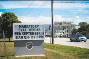  ?? Charles Mostoller / Bloomberg ?? A vehicle passes a sign displaying informatio­n for mandatory evacuation­s ahead of Hurricane Florence in the Wrightsvil­le Beach neighborho­od of Wilmington, N.C., on Tuesday. Hurricane Florence could be the most powerful storm to make landfall in North Carolina if prediction­s hold. No Category 4 hurricane has ever made landfall in the state.