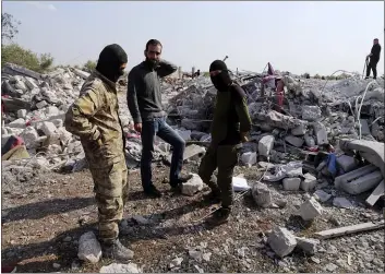  ?? GHAITH ALSAYED — THE ASSOCIATED PRESS ?? People look at a destroyed houses near the village of Barisha, in Idlib province, Syria, Sunday after an operation by the U.S. military which targeted Abu Bakr al-Baghdadi, the shadowy leader of the Islamic State group. President Donald Trump says Abu Bakr al-Baghdadi is dead after a U.S. military operation in Syria targeted the Islamic State group leader.