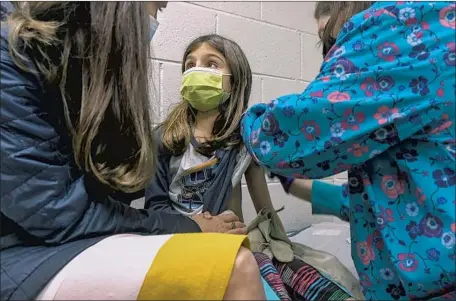  ?? Shawn Rocco Duke Health ?? ALEJANDRA GERARDO, 9, with her mother, Dr. Susanna Naggie, is injected for Pfizer’s clinical trial at Duke Health in Durham, N.C.