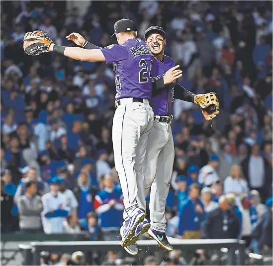  ?? Andy Cross, The Denver Post ?? Rockies first baseman Ryan McMahon, left, and third baseman Nolan Arenado celebrate their 21, 13inning victory Tuesday night over the Chicago Cubs at Wrigley Field in the National League wildcard game. Arenado had a sacrifice fly in the first inning, scoring Charlie Blackmon.