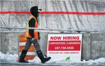  ?? AP PHOTO/ROBERT F. BUKATY ?? A worker passes a hiring sign at a constructi­on site Jan. 25 in Portland, Maine.