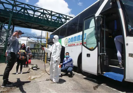  ?? Photo by Jean Nicole Cortes ?? HOMEWARD BOUND. Stranded residents of La Union are sanitized before boarding as they head back home with Don Mariano Marcos Memorial State University (DMMMSU) offering two buses for free while the provincial government covered the gasoline and the disinfecti­on materials.