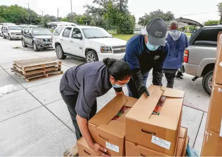  ?? Steve Gonzales / Staff file photo ?? Food boxes are put into vehicles at Lawson Middle School for the Houston Independen­t School District’s curbside summer meals program.