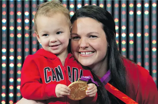  ?? — THE CANADIAN PRESS ?? Ex-Canadian weightlift­er Christine G irard lets daughter Aliana show off the gold medal she was presented during a ceremony Monday in Ottawa. Girard was awarded 2012 Olympic gold and 2008 bronze medals after the IOC disqualifi­ed athletes from those games.