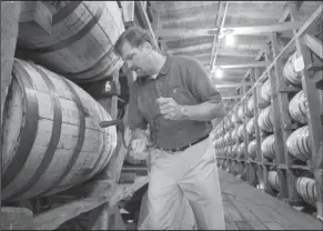  ??  ?? Whiskey challenge: Jeff Arnett, the master distiller at the Jack Daniel Distillery in Lynchburg, Tenn., drills a hole in a barrel of whiskey in one of the aging houses at the distillery.